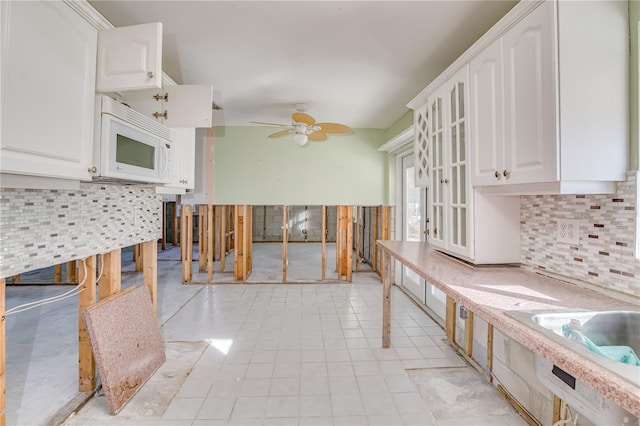 kitchen featuring decorative backsplash, white cabinetry, and ceiling fan