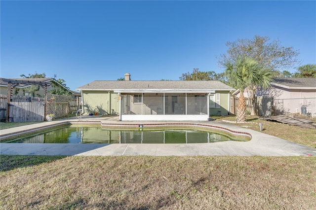 back of property featuring a fenced in pool, a lawn, and a sunroom