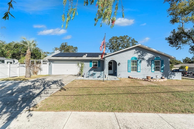 ranch-style house featuring a front lawn, a garage, and solar panels