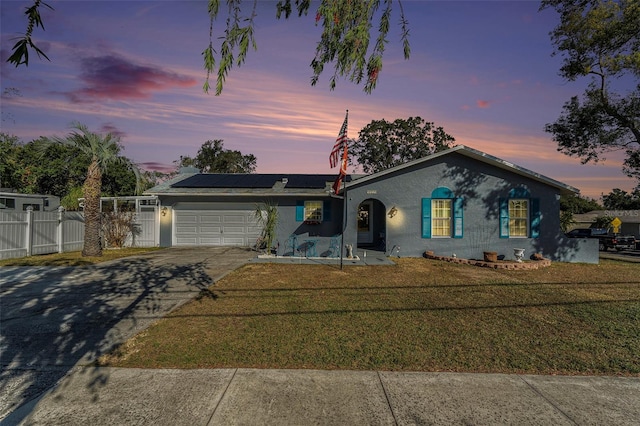 ranch-style home featuring a lawn, solar panels, and a garage