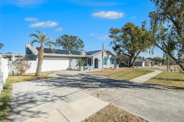 ranch-style house featuring a front lawn, a garage, and solar panels