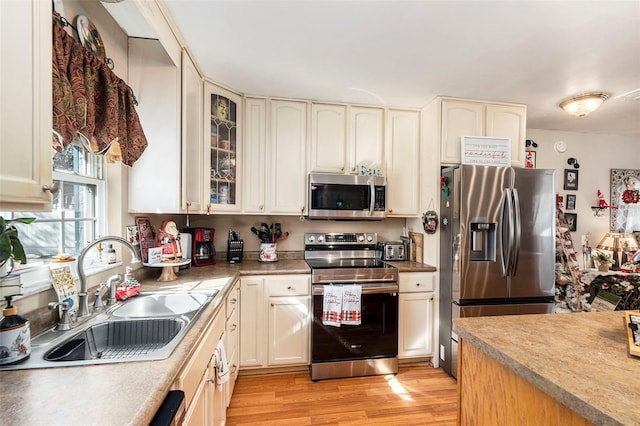 kitchen featuring cream cabinets, sink, light hardwood / wood-style floors, and appliances with stainless steel finishes