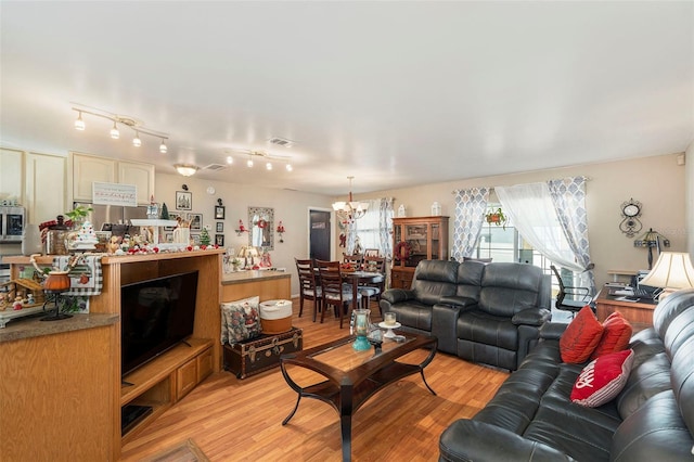 living room featuring light wood-type flooring, rail lighting, and a notable chandelier