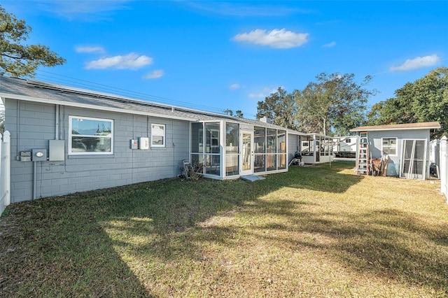 rear view of house featuring a lawn and a storage unit