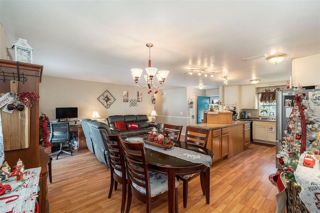 dining space featuring sink, light hardwood / wood-style floors, and an inviting chandelier