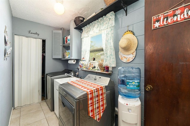 clothes washing area featuring separate washer and dryer, light tile patterned floors, and a textured ceiling