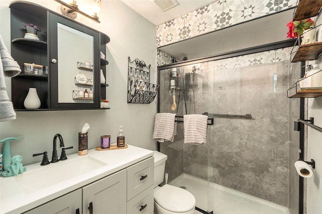 bathroom with vanity, toilet, and a shower with shower door