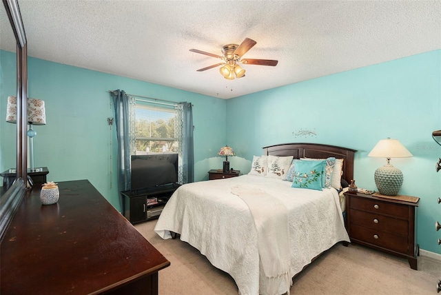 bedroom featuring ceiling fan, light colored carpet, and a textured ceiling