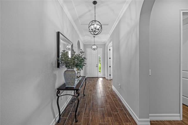 hall featuring crown molding, dark wood-type flooring, and an inviting chandelier