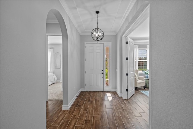 foyer entrance with dark hardwood / wood-style flooring, ornamental molding, and an inviting chandelier