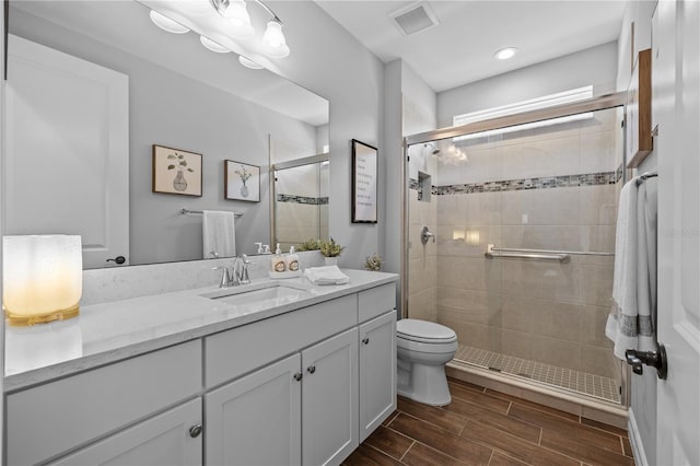 bathroom featuring vanity, toilet, and a shower with door