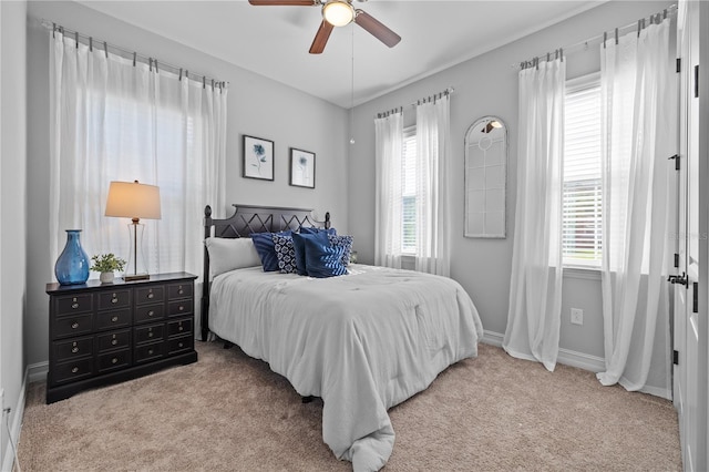 bedroom featuring multiple windows, ceiling fan, and light colored carpet