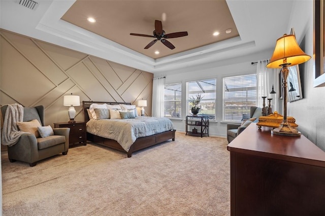 bedroom featuring ceiling fan, a raised ceiling, and light carpet