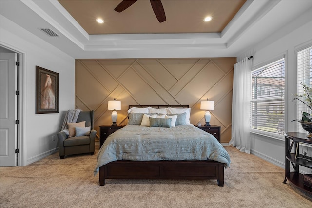 carpeted bedroom featuring ceiling fan and a tray ceiling