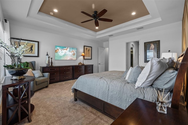 carpeted bedroom with ceiling fan and a raised ceiling