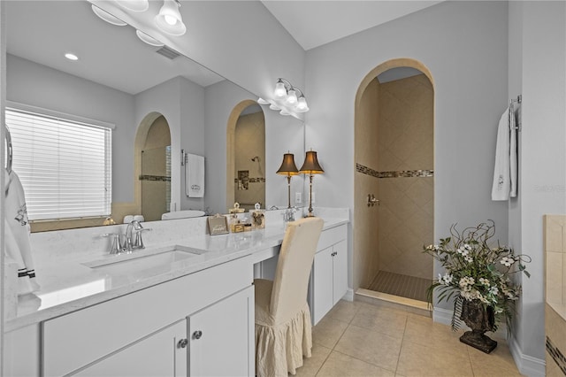 bathroom with tile patterned flooring, vanity, and a tile shower