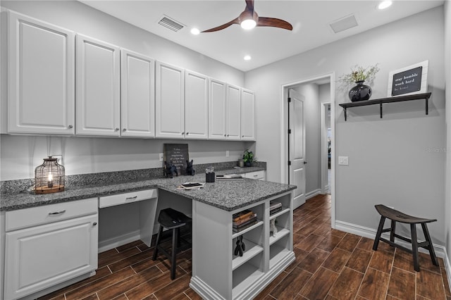 kitchen featuring white cabinetry, dark wood-type flooring, and built in desk