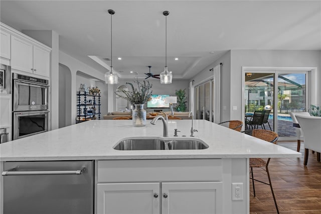 kitchen featuring sink, stainless steel appliances, a kitchen breakfast bar, a kitchen island with sink, and white cabinets