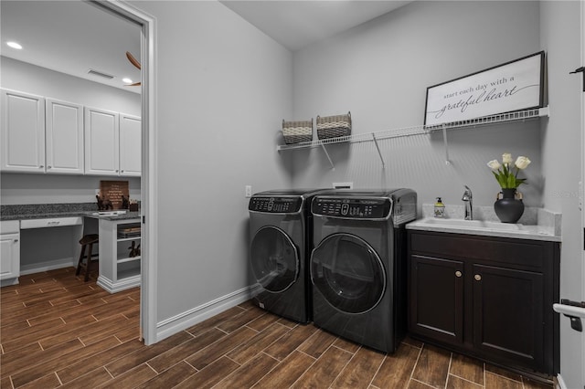 laundry area featuring separate washer and dryer, dark hardwood / wood-style floors, cabinets, and sink