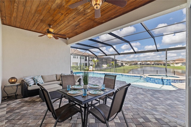 view of patio featuring glass enclosure, a swimming pool with hot tub, and a water view