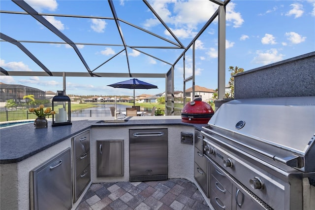 view of patio featuring a lanai, grilling area, a water view, and exterior kitchen