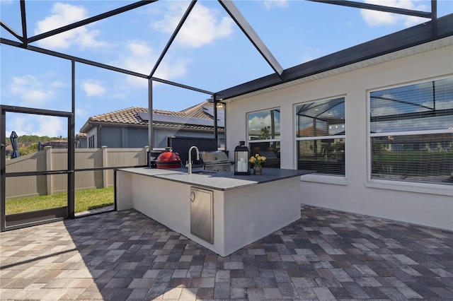 view of patio / terrace featuring glass enclosure, an outdoor bar, and an outdoor kitchen