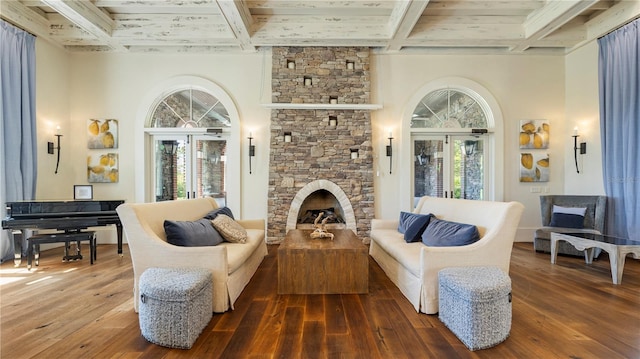 living room with a stone fireplace, dark hardwood / wood-style flooring, beamed ceiling, and french doors