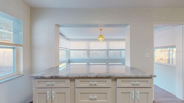 kitchen with light hardwood / wood-style floors, light stone countertops, and hanging light fixtures