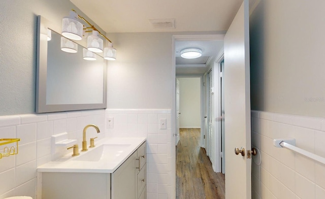 bathroom with hardwood / wood-style floors, vanity, and tile walls