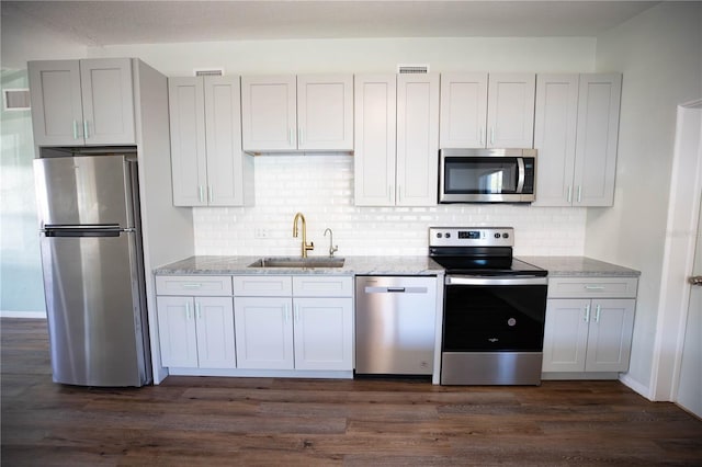 kitchen featuring dark wood-type flooring, sink, light stone countertops, appliances with stainless steel finishes, and tasteful backsplash