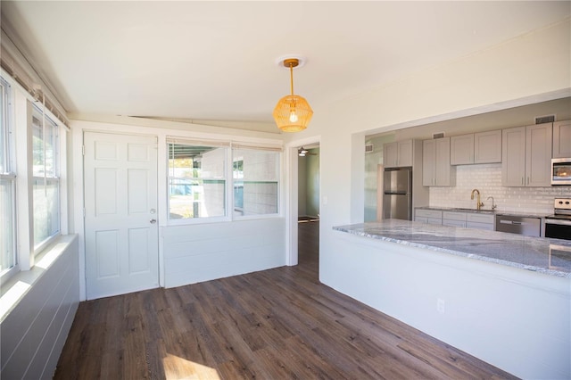 kitchen featuring gray cabinets, tasteful backsplash, decorative light fixtures, light stone counters, and stainless steel appliances