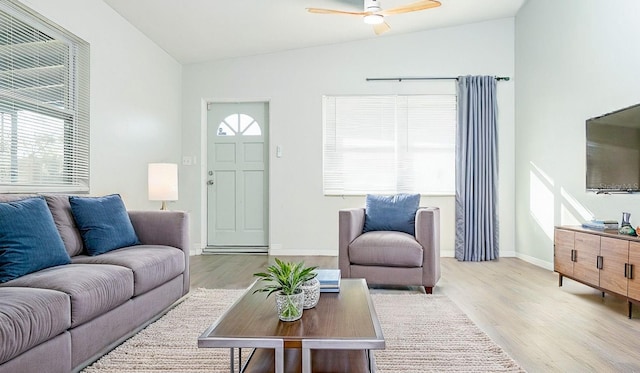 living room featuring ceiling fan, lofted ceiling, and light wood-type flooring