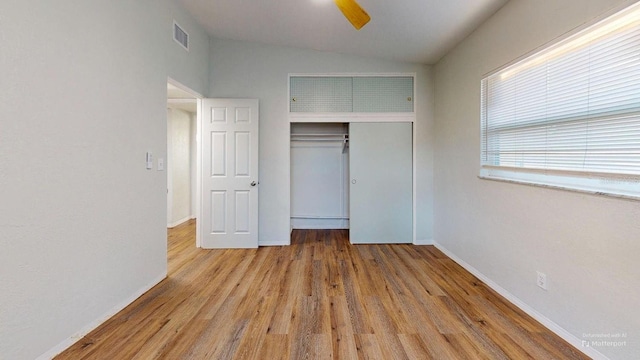 unfurnished bedroom featuring ceiling fan, a closet, light hardwood / wood-style floors, and vaulted ceiling