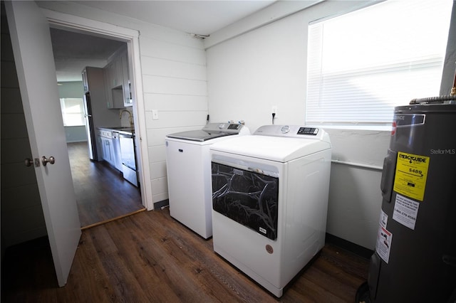 clothes washing area with washer and dryer, sink, dark wood-type flooring, and water heater