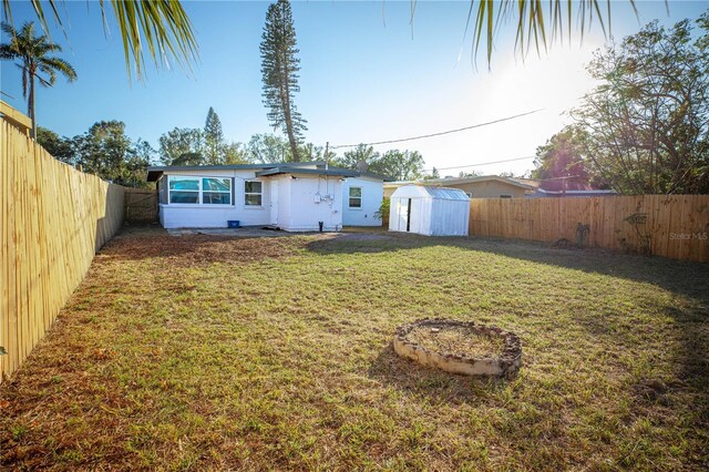 back of house with a lawn and a storage shed