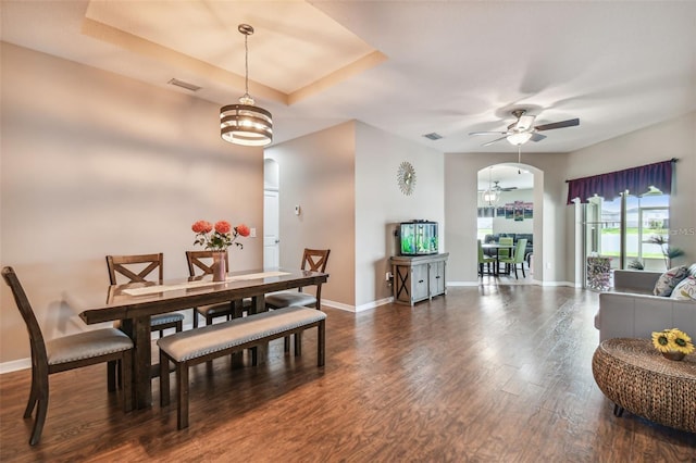 dining area with ceiling fan with notable chandelier and dark hardwood / wood-style flooring