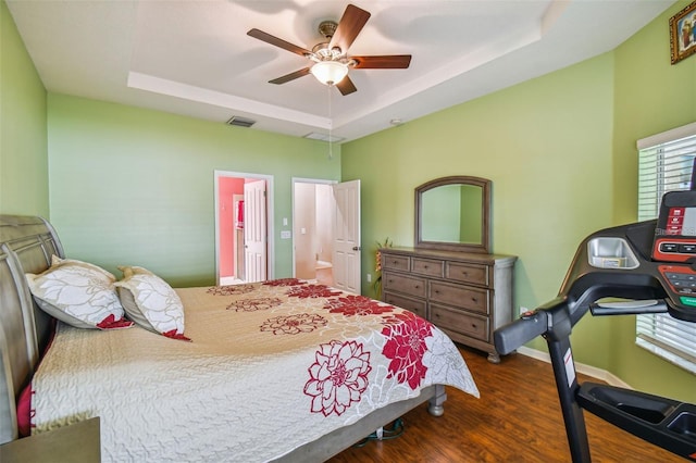 bedroom featuring ceiling fan, a raised ceiling, and dark wood-type flooring