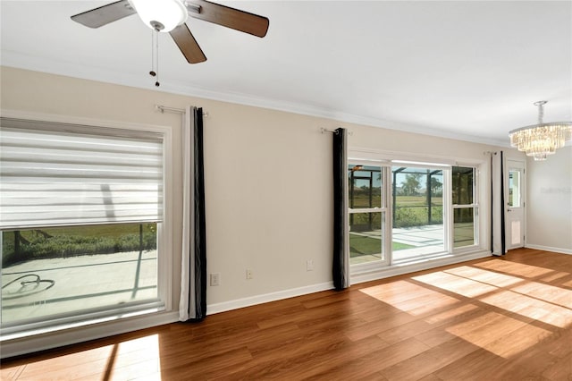 unfurnished room with wood-type flooring, ceiling fan with notable chandelier, ornamental molding, and a healthy amount of sunlight