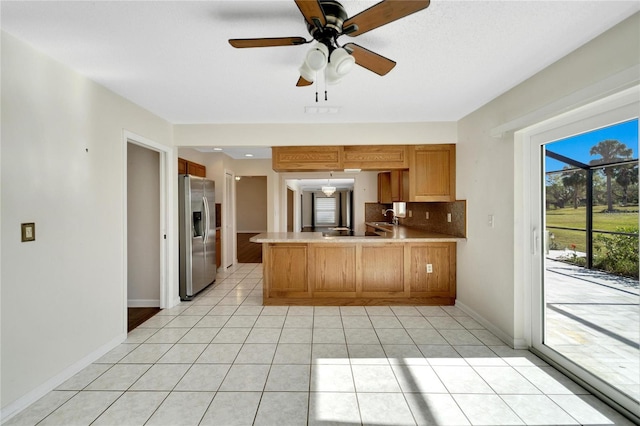 kitchen with kitchen peninsula, backsplash, ceiling fan, light tile patterned floors, and stainless steel fridge with ice dispenser