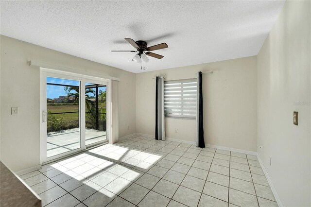 spare room featuring ceiling fan, light tile patterned flooring, and a textured ceiling