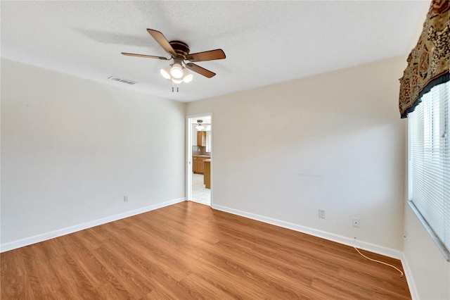 spare room with ceiling fan, light hardwood / wood-style floors, and a textured ceiling