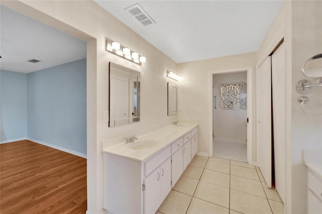 bathroom with hardwood / wood-style floors, vanity, and a textured ceiling