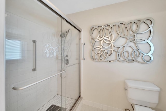 bathroom with tile patterned floors, a shower with shower door, and toilet