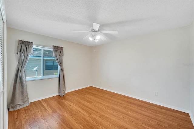 empty room with ceiling fan, light hardwood / wood-style floors, and a textured ceiling