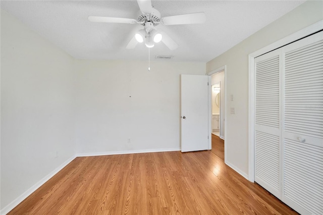 unfurnished bedroom featuring a textured ceiling, a closet, light hardwood / wood-style floors, and ceiling fan