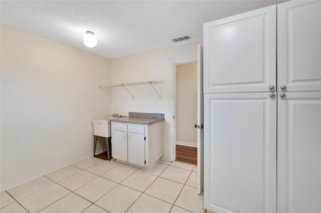 clothes washing area with light tile patterned floors and a textured ceiling