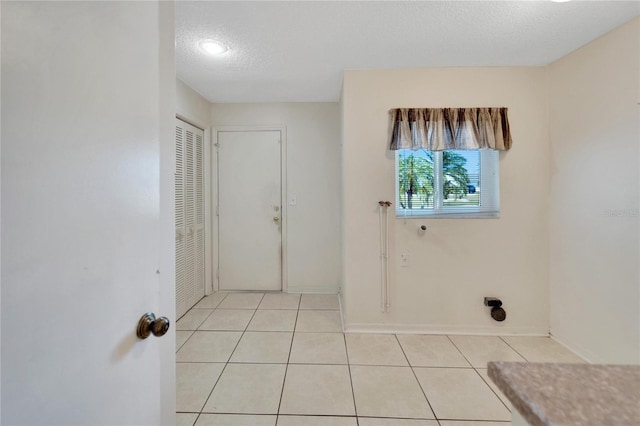 laundry room with light tile patterned flooring and a textured ceiling