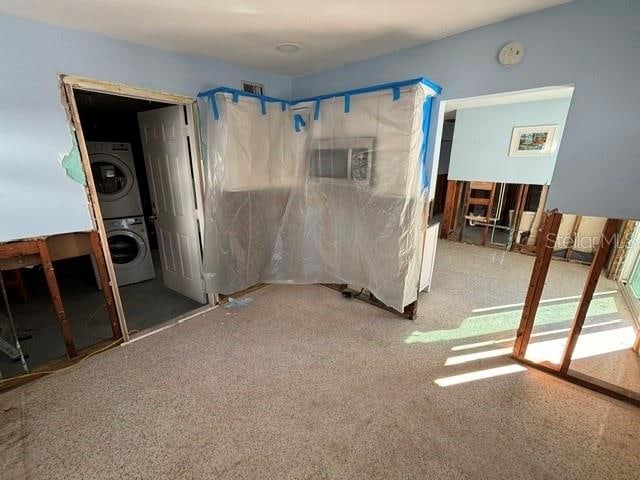 bedroom with stacked washer / drying machine and radiator heating unit