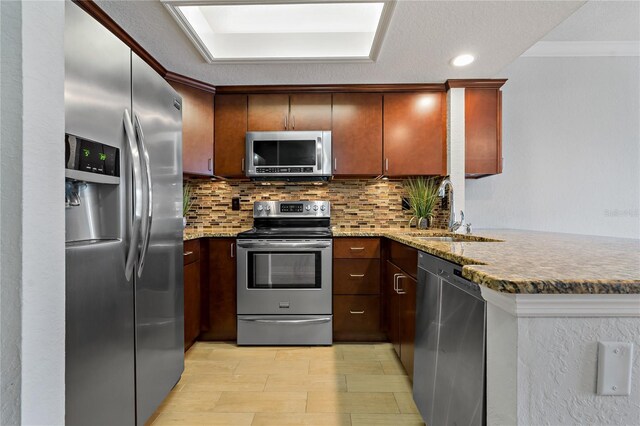 kitchen with sink, decorative backsplash, light stone countertops, kitchen peninsula, and stainless steel appliances