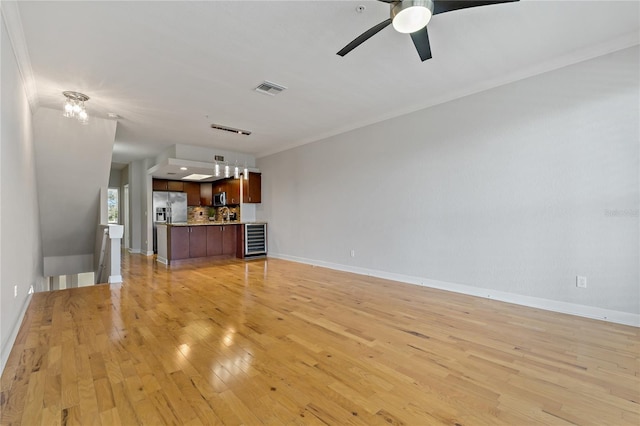 unfurnished living room featuring ceiling fan, light hardwood / wood-style floors, ornamental molding, and beverage cooler